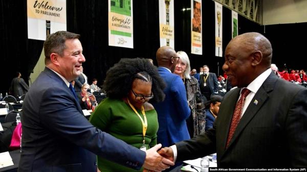 FILE - South African President Cyril Ramaphosa, right, greets opposition Democratic Alliance (DA) leader, John Steenhuisen, left, at the first sitting of Parliament since elections, in Cape Town, June 14, 2024. 