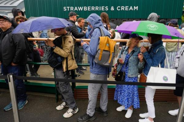 Spectators with umbrellas queue for strawberries at the Wimbledon tennis champio<em></em>nships in London