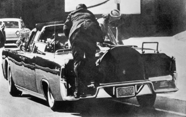 Just after John F. Kennedy was shot, Jacqueline Kennedy stands up in the presidential car to lift up the body of her husband. In the foreground, a Secret Service agent jumps o<em></em>nto the back fender of the car.